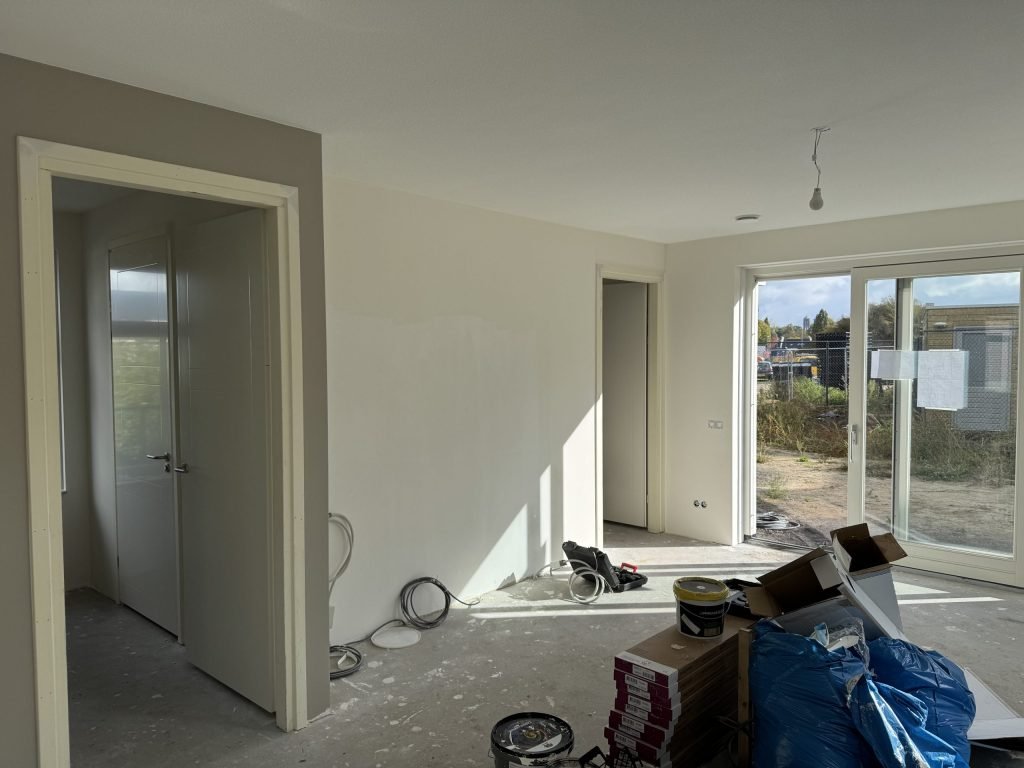 Nieuwe woning vlak na het behangen: lichte wanden, materiaal en dozen nog op de betonvloer