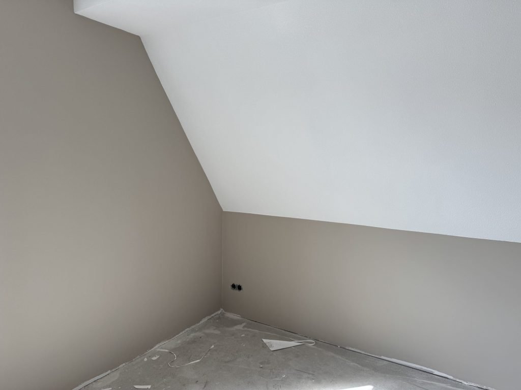 Slaapkamer onder een schuin dak met zandkleurige wanden en een witte schuinte