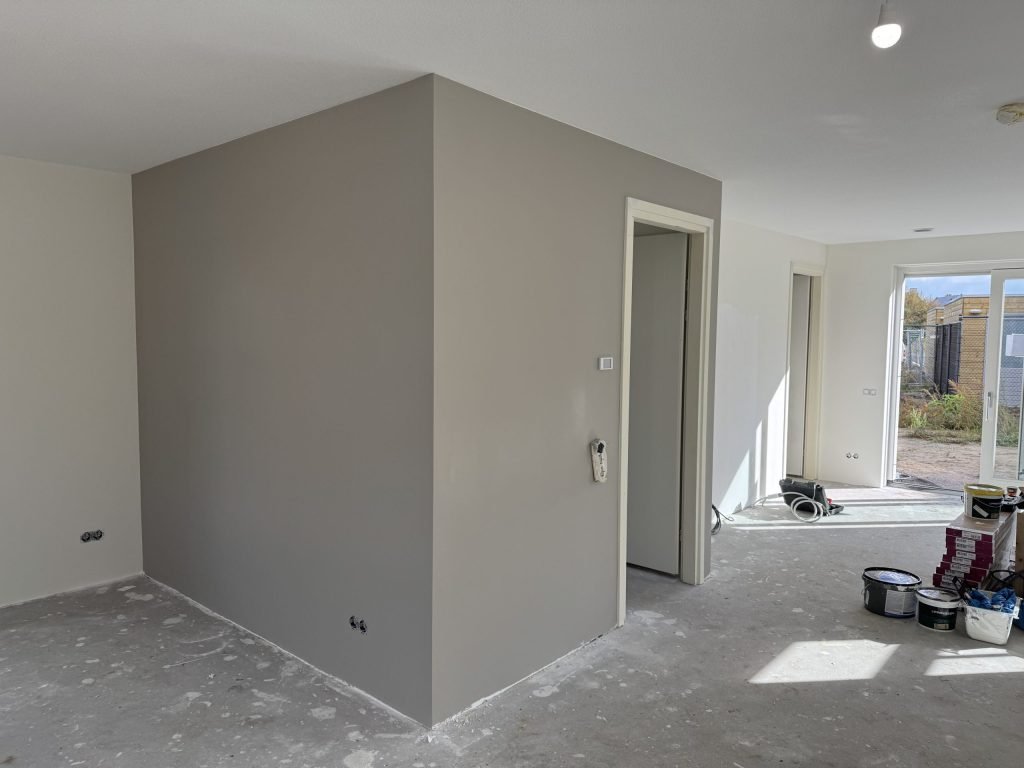 Net opgeleverde benedenverdieping met een warmgrijs gesausde wand rond de meterkast
